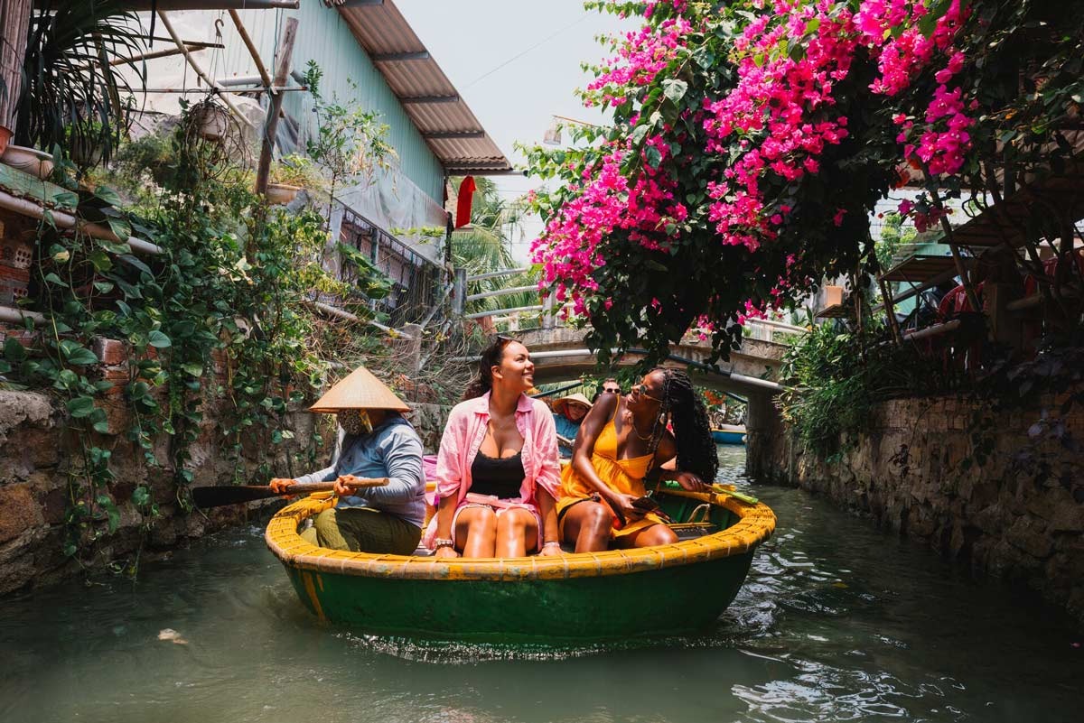 People enjoying a basket-shaped boat ride in a narrow river flowers around in Vietnam.