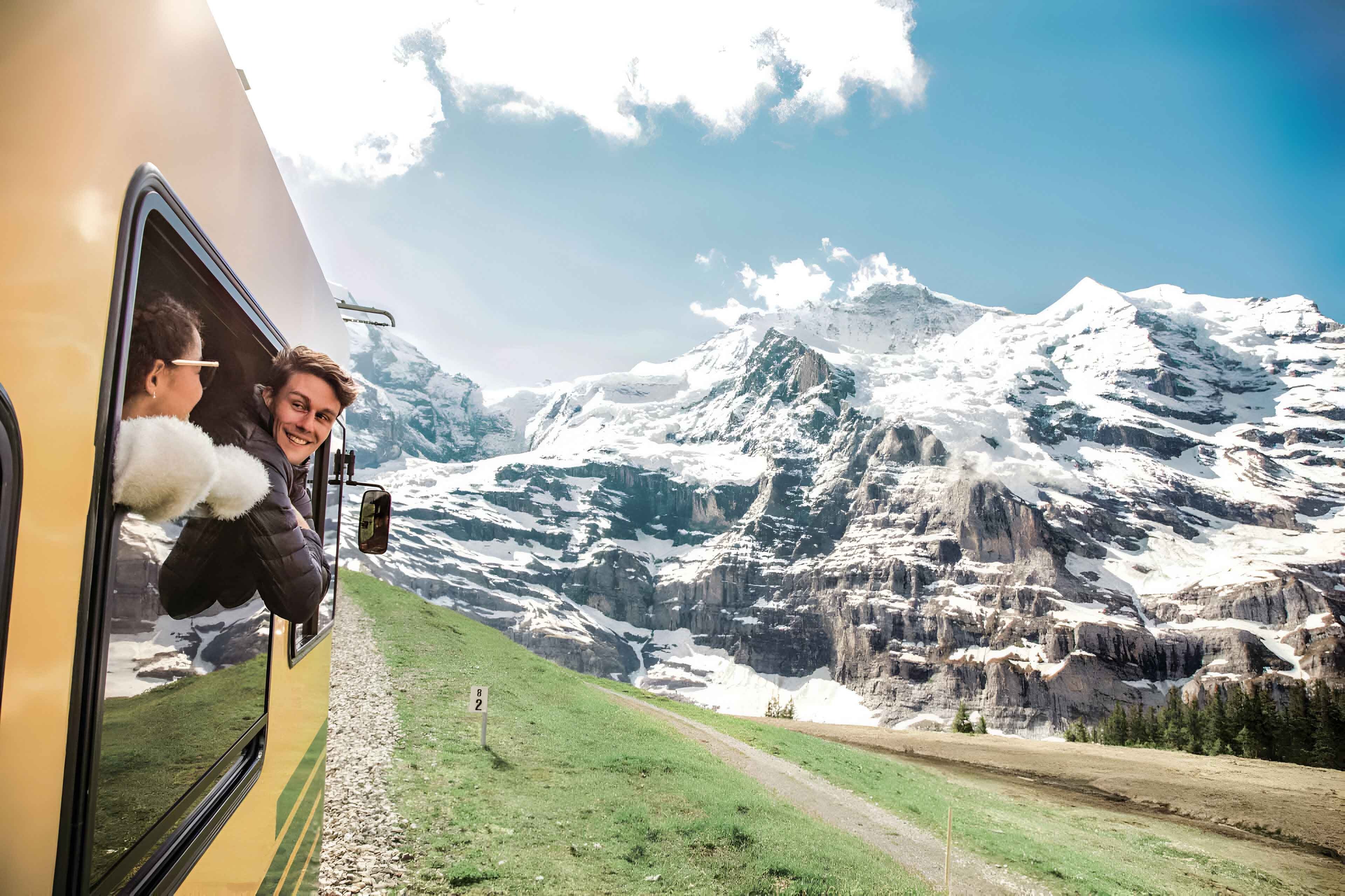 Two Young Happy People Enjoying The Snowy Mountains View From A Train