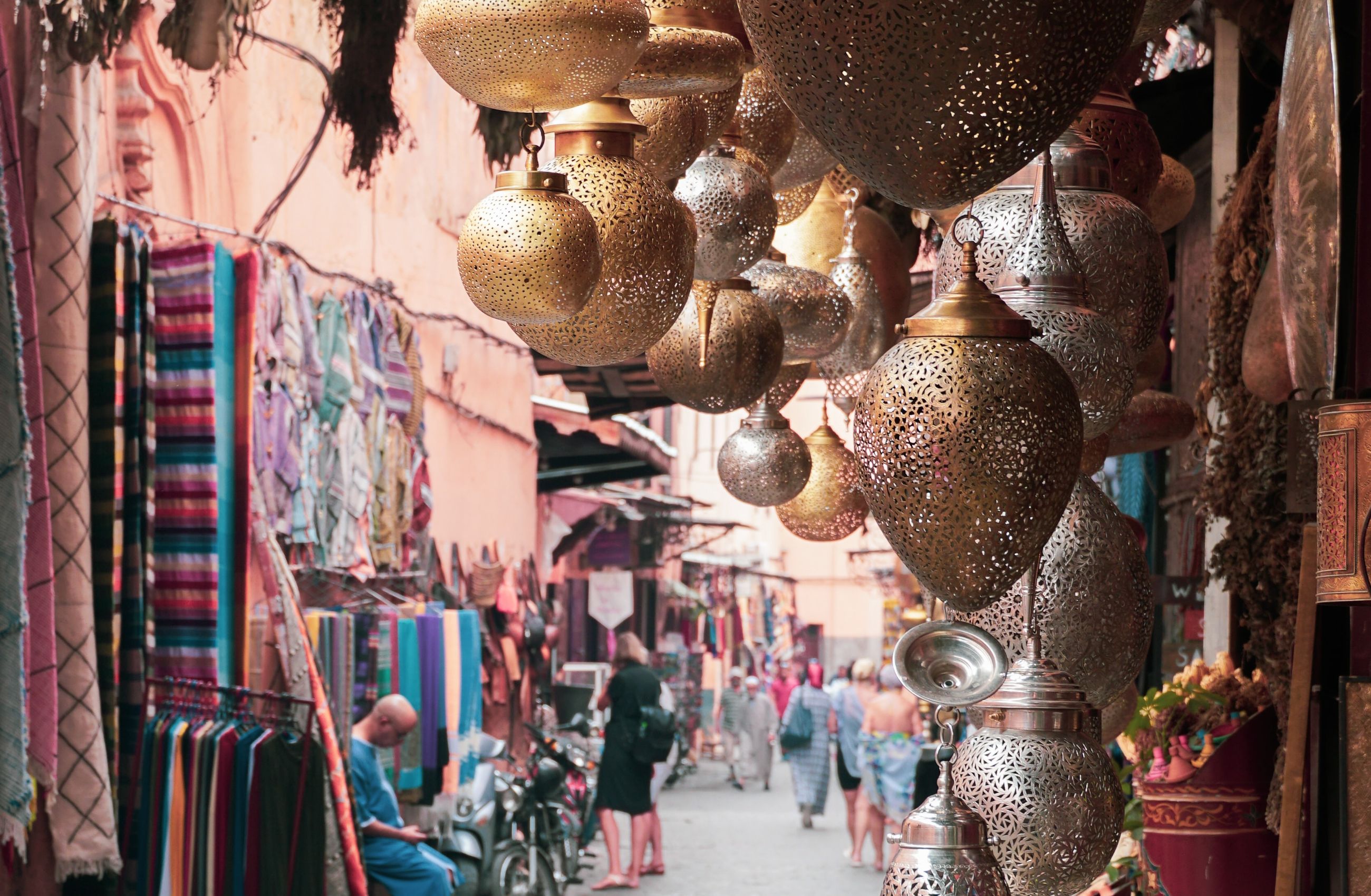 A narrow alleyway in a market in Cairo, Egypt, full of stalls selling fabrics and decorative lamps.