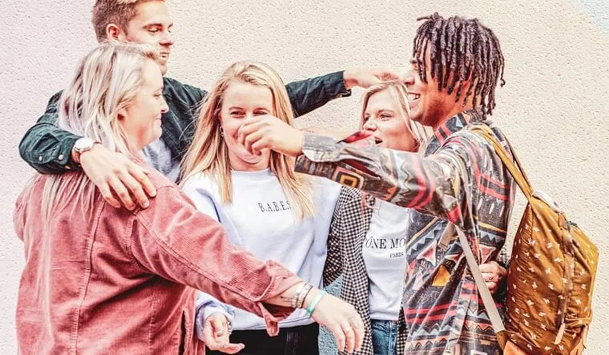 Group of young people in colorful clothes hugging 