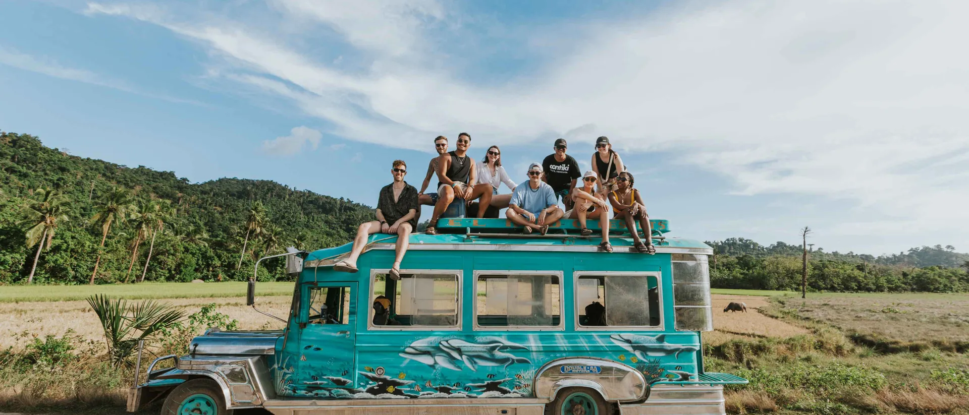 Group Of Young Travelers Sitting On Top Of Cool Bus Philppines