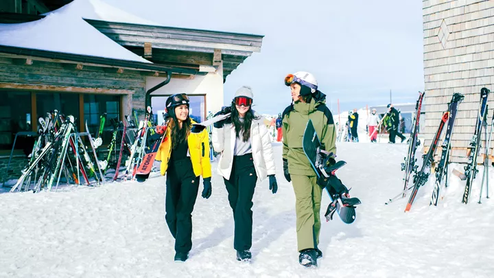 Group of Travellers walking in the snow carrying skis in Hopfgarten, Austria
