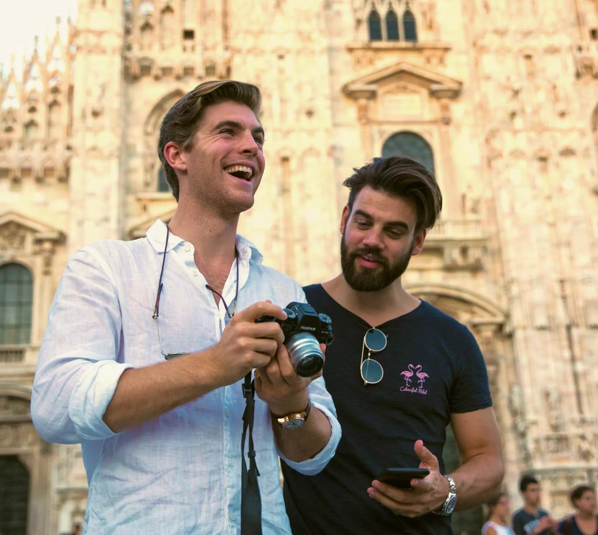 Two Contiki travellers reviewing photos in front of Milan Cathedral (Duomo di Milano), capturing memories while exploring Milan on the Tuscany, Milan & Venice 35 to 45 Tour