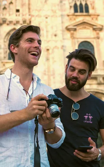 Two Contiki travellers reviewing photos in front of Milan Cathedral (Duomo di Milano), capturing memories while exploring Milan on the Tuscany, Milan & Venice 35 to 45 Tour
