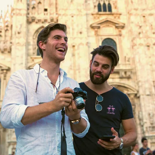Two Contiki travellers reviewing photos in front of Milan Cathedral (Duomo di Milano), capturing memories while exploring Milan on the Tuscany, Milan & Venice 35 to 45 Tour