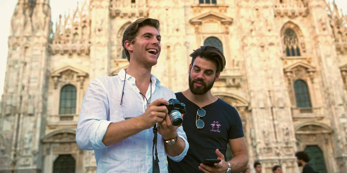 Two Contiki travellers reviewing photos in front of Milan Cathedral (Duomo di Milano), capturing memories while exploring Milan on the Tuscany, Milan & Venice 35 to 45 Tour