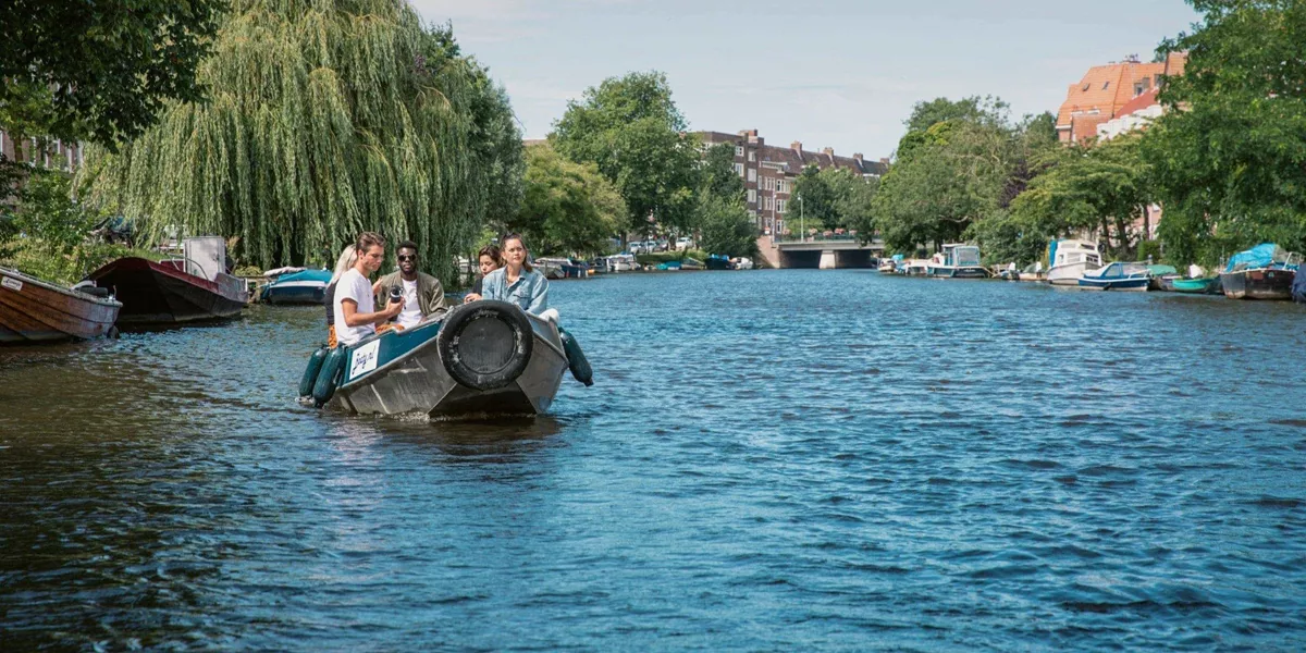 Contiki travellers cruise along Amsterdam's canals in a small boat on the European Encounter Tour