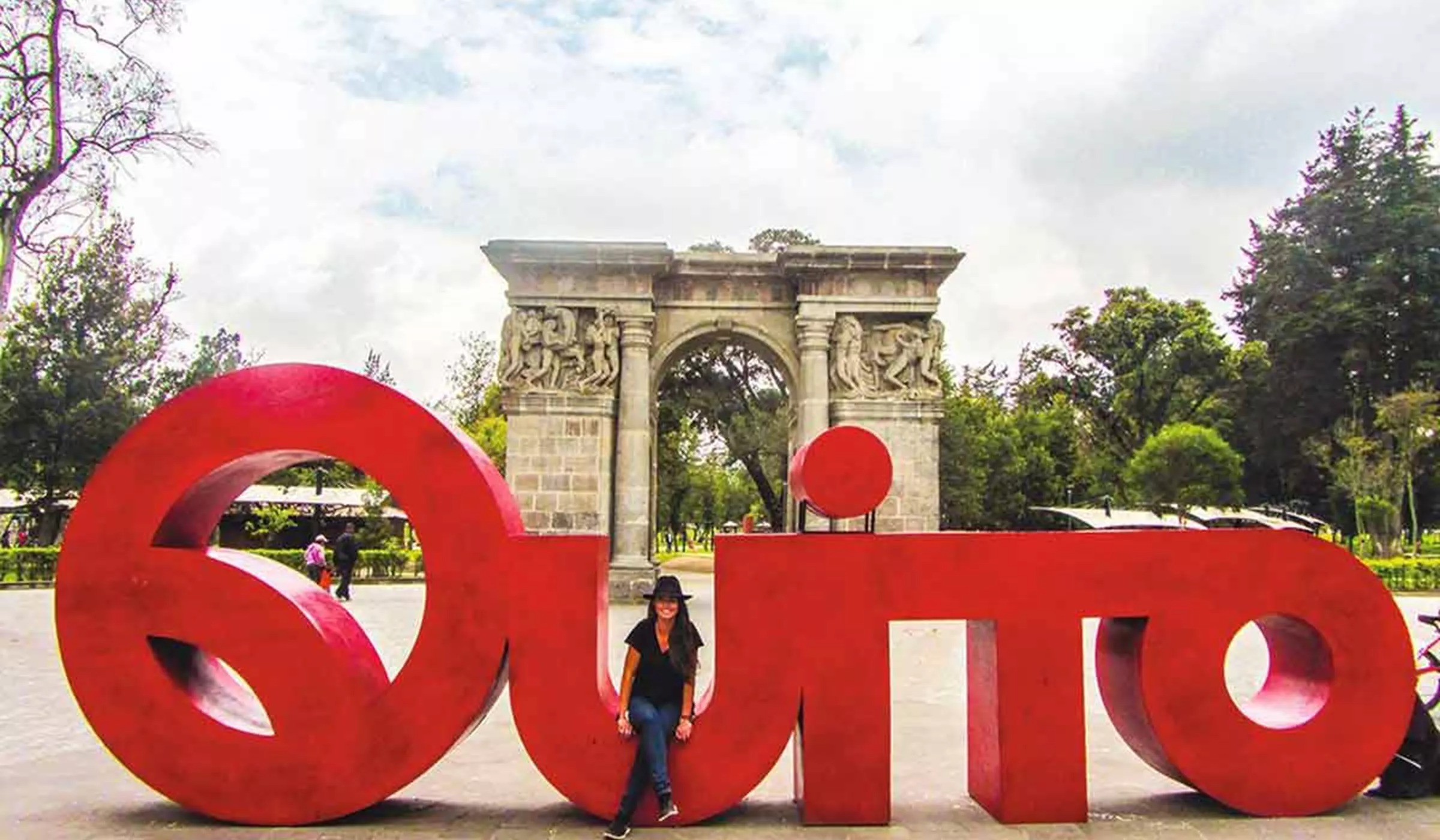 Woman sitting on a large Quito sign.