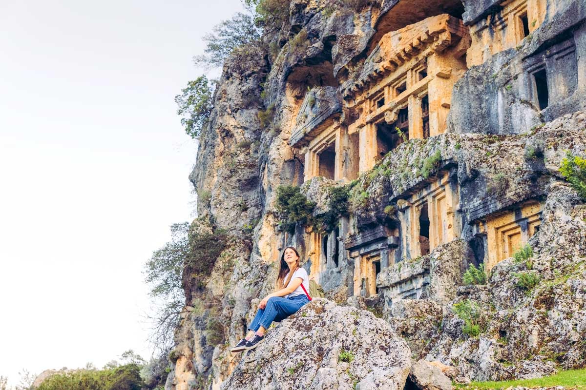 Woman sitting on a rock landmark as her background