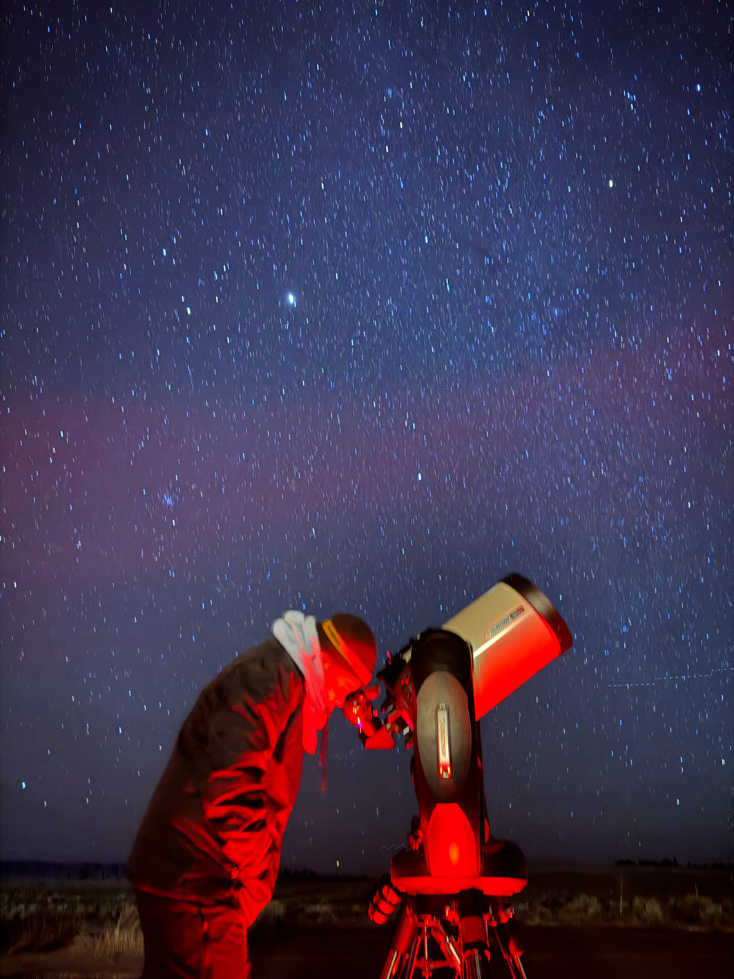 A person peers through a telescope under a starry night sky, Bryce Canyon, USA