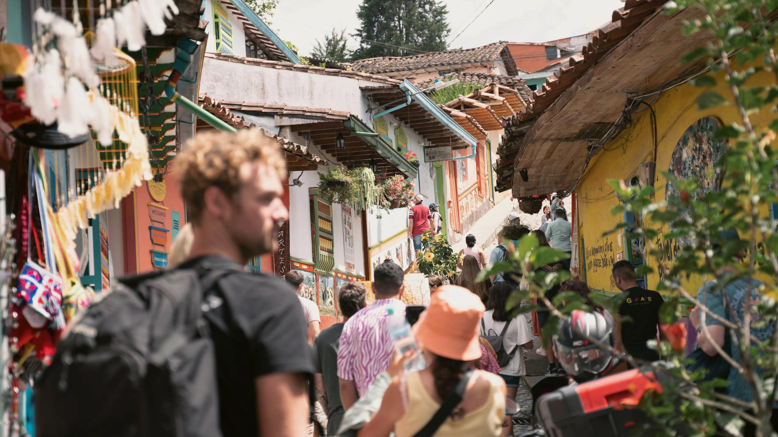Travellers exploring the vibrant colourful colonial streets of Guatapé in Antioquia Colombia lined with painted buildings and artisan market stalls - Contiki Best of Colombia Tour