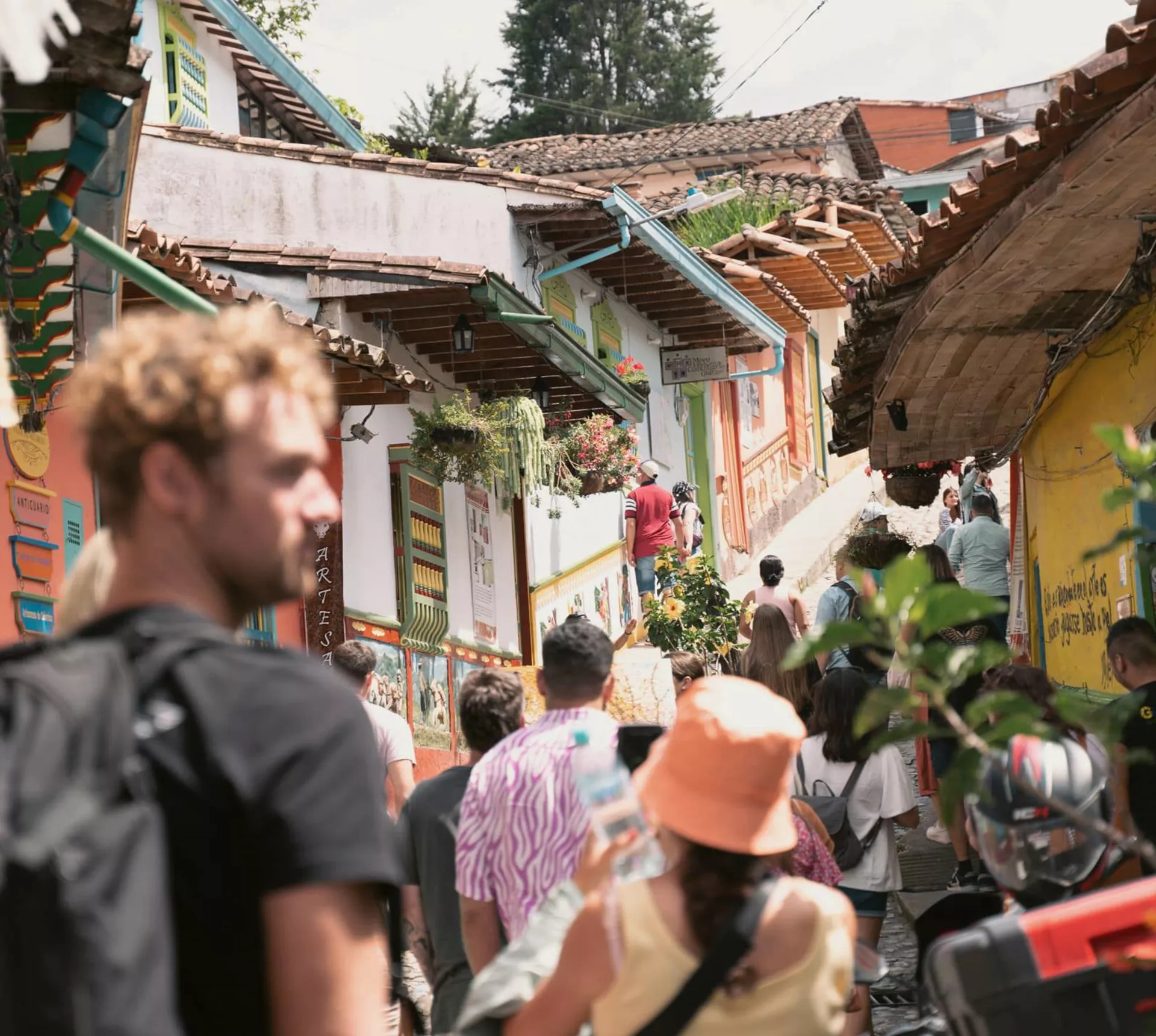 Travellers exploring the vibrant colourful colonial streets of Guatapé in Antioquia Colombia lined with painted buildings and artisan market stalls - Contiki Best of Colombia Tour