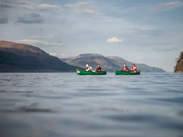 people in boats at a lake mountains at the back