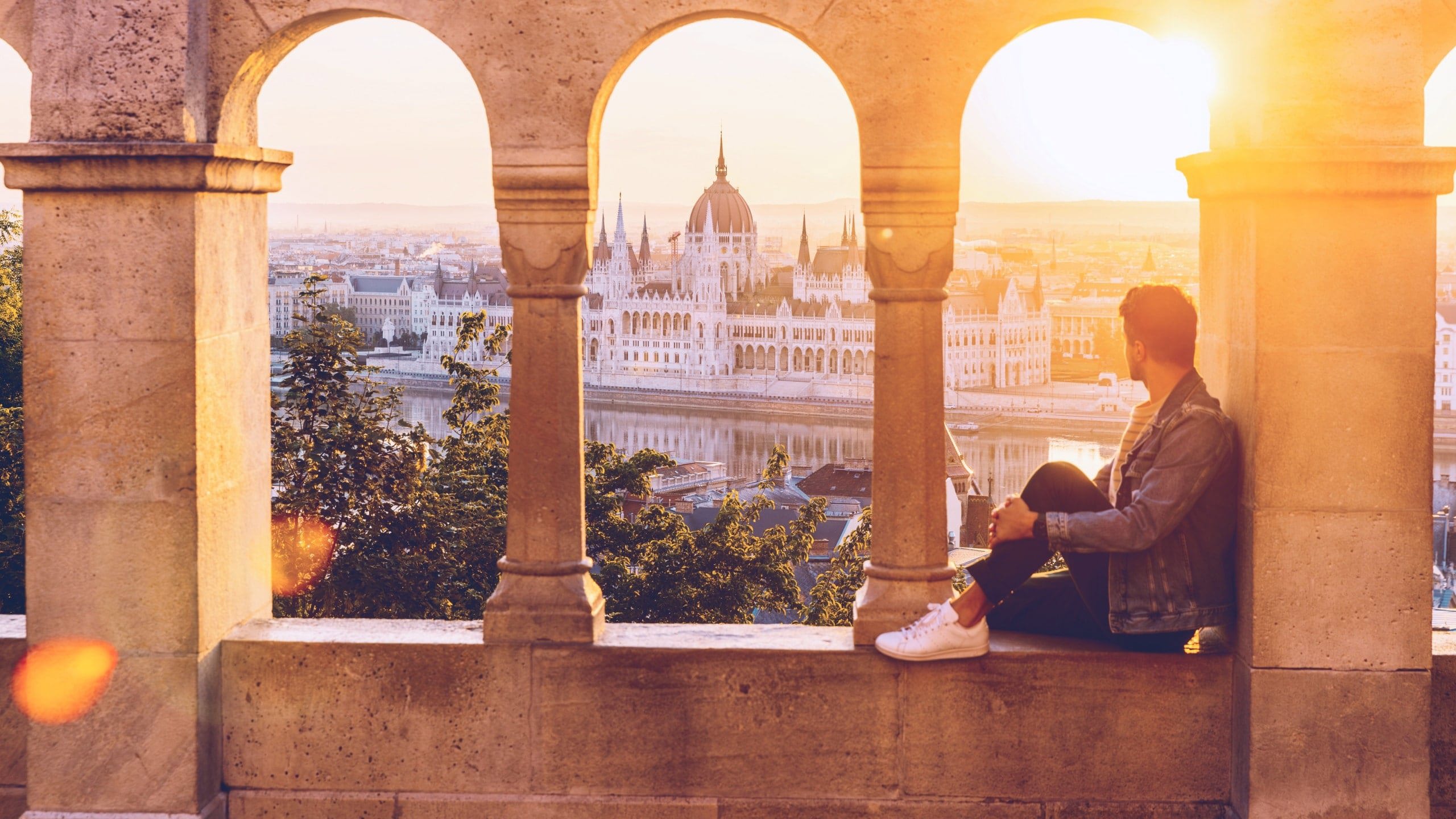 A Contiki traveller watches the sunset over the Hungarian Parliament Building from Fisherman's Bastion in Budapest on the London to Vienna Trail