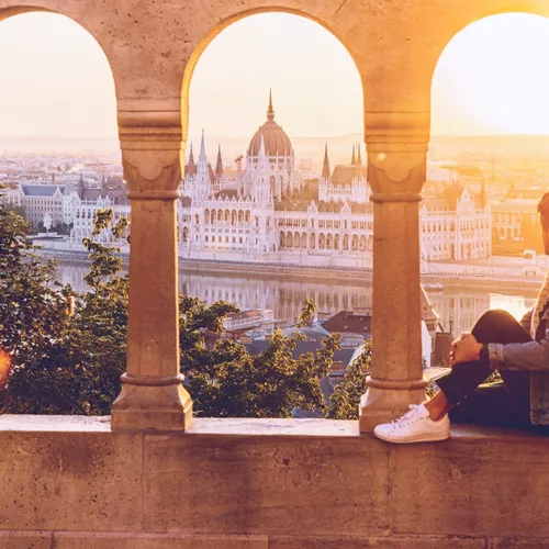 A Contiki traveller watches the sunset over the Hungarian Parliament Building from Fisherman's Bastion in Budapest on the London to Vienna Trail