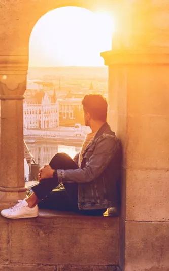 A Contiki traveller watches the sunset over the Hungarian Parliament Building from Fisherman's Bastion in Budapest on the London to Vienna Trail