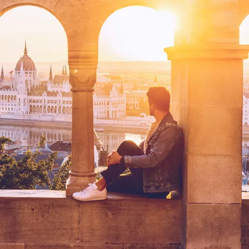 A Contiki traveller watches the sunset over the Hungarian Parliament Building from Fisherman's Bastion in Budapest on the London to Vienna Trail