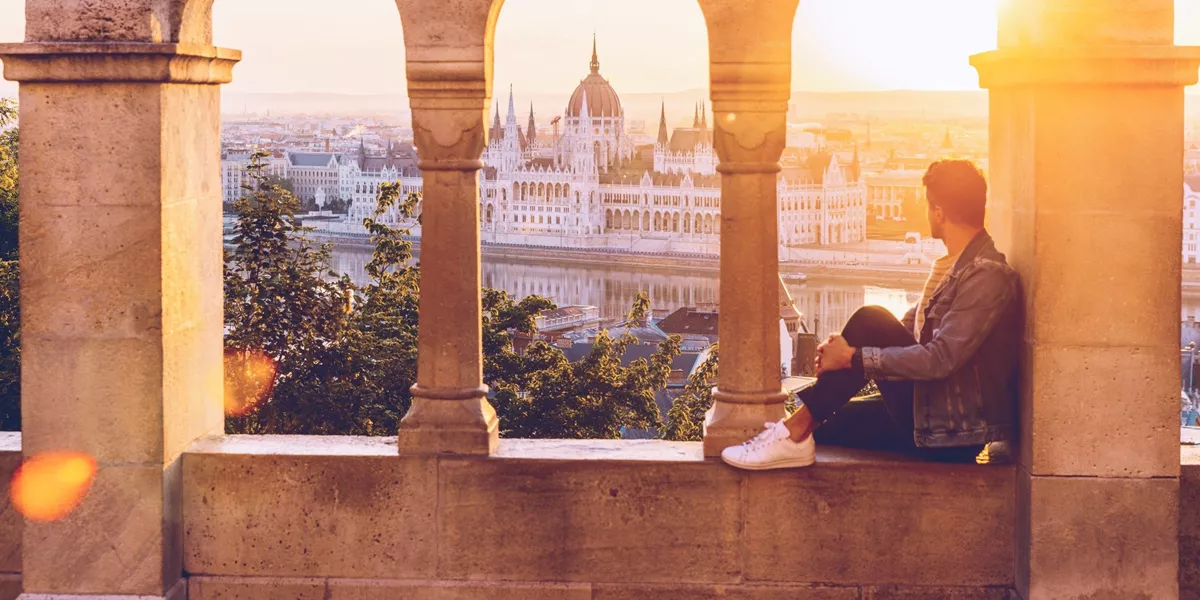 A Contiki traveller watches the sunset over the Hungarian Parliament Building from Fisherman's Bastion in Budapest on the London to Vienna Trail