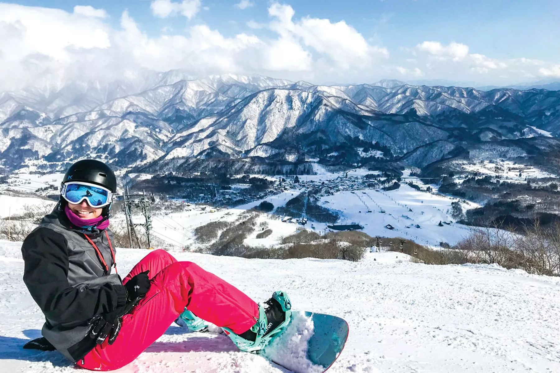 Person is smiling to capture the scenic beauty while snowboarding.