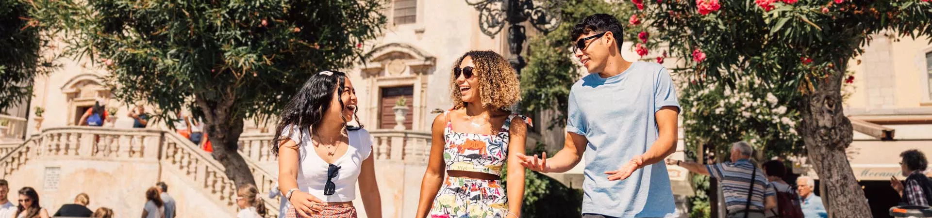 group of travelers talking and ;laughing in the sun sicily