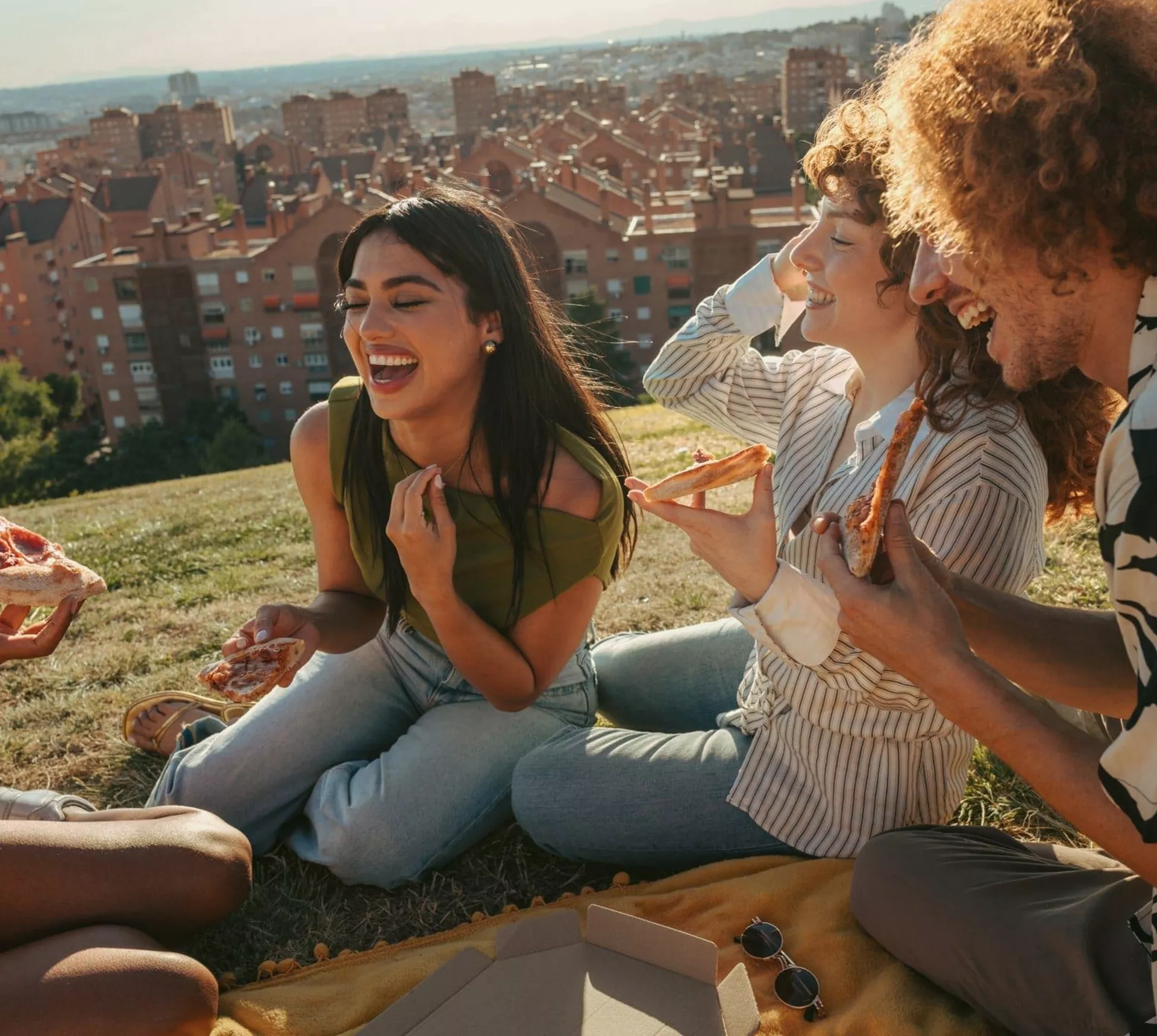 Travellers share pizza and laughter during a picnic overlooking the city on the Contiki Barcelona to Madrid Tour