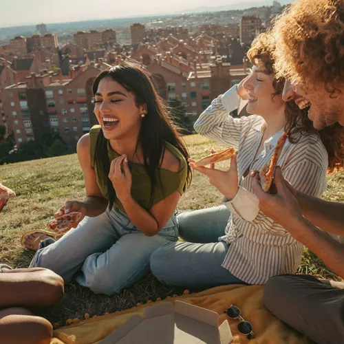 Travellers share pizza and laughter during a picnic overlooking the city on the Contiki Barcelona to Madrid Tour
