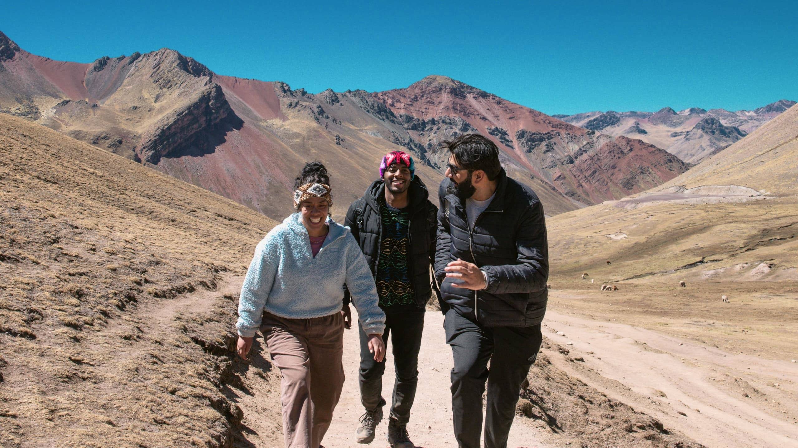 Contiki travellers hiking through the colourful Andes Mountains near Rainbow Mountain, Peru, surrounded by dramatic alpine scenery on the Ultimate South America Tour