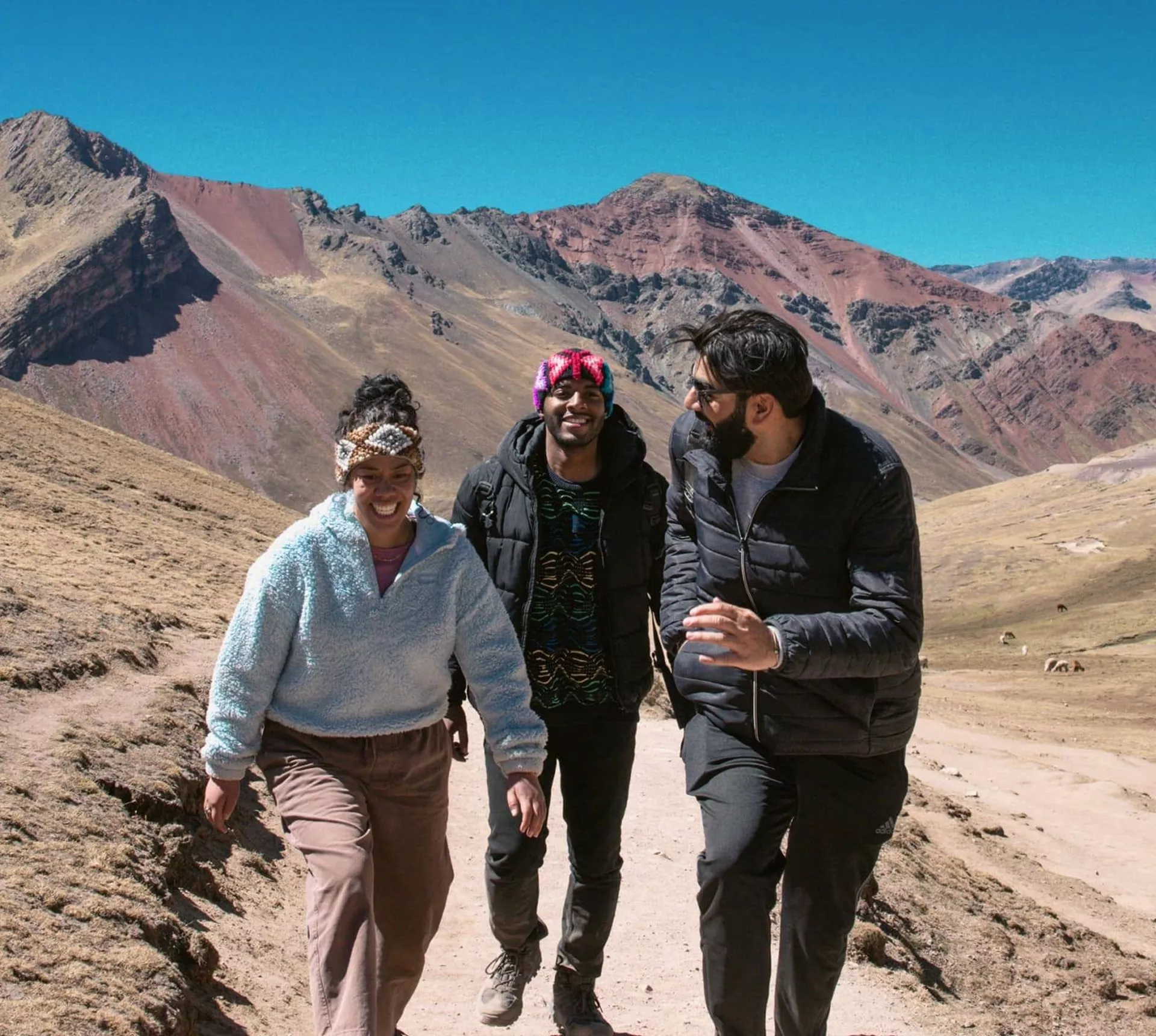 Contiki travellers hiking through the colourful Andes Mountains near Rainbow Mountain, Peru, surrounded by dramatic alpine scenery on the Ultimate South America Tour