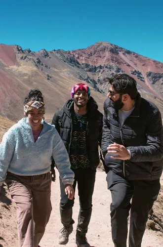 Contiki travellers hiking through the colourful Andes Mountains near Rainbow Mountain, Peru, surrounded by dramatic alpine scenery on the Ultimate South America Tour