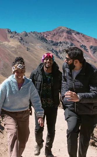 Contiki travellers hiking through the colourful Andes Mountains near Rainbow Mountain, Peru, surrounded by dramatic alpine scenery on the Ultimate South America Tour