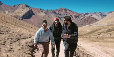 Contiki travellers hiking through the colourful Andes Mountains near Rainbow Mountain, Peru, surrounded by dramatic alpine scenery on the Ultimate South America Tour