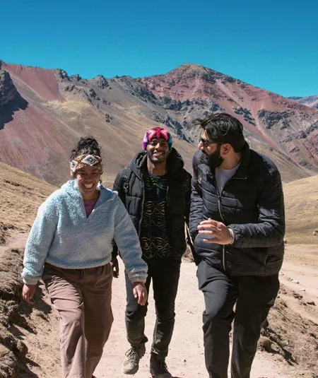 Contiki travellers hiking through the colourful Andes Mountains near Rainbow Mountain, Peru, surrounded by dramatic alpine scenery on the Ultimate South America Tour