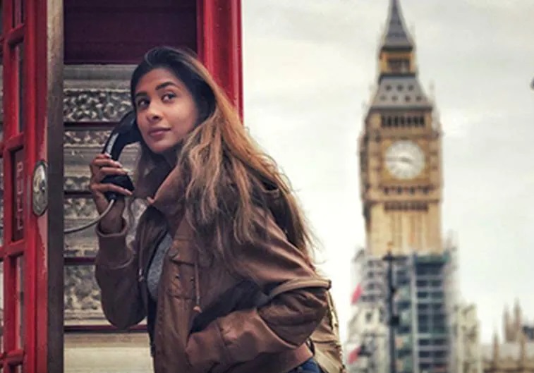 A woman holding a telephone receiver in a telephone booth