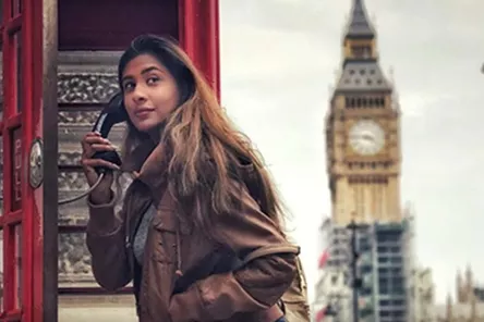 A woman holding a telephone receiver in a telephone booth