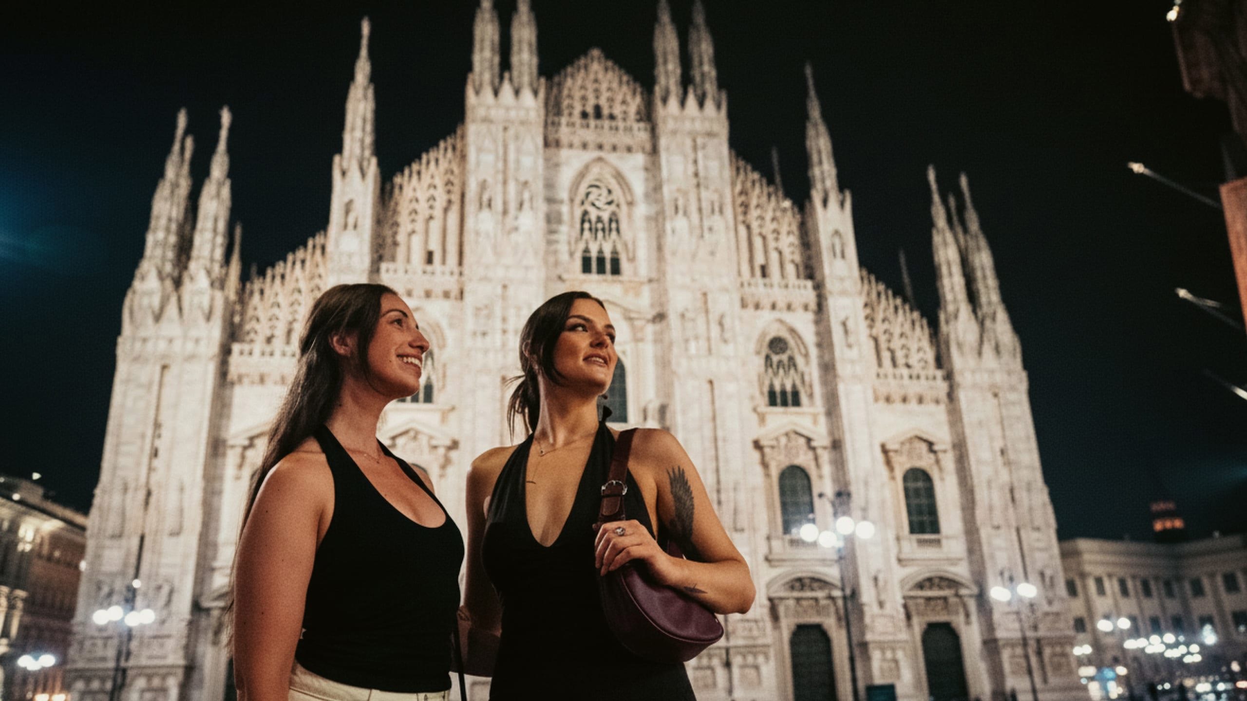 Two girls admiring Milan Cathedral (Duomo di Milano) at night - Contiki Paris to Rome by Train Tour