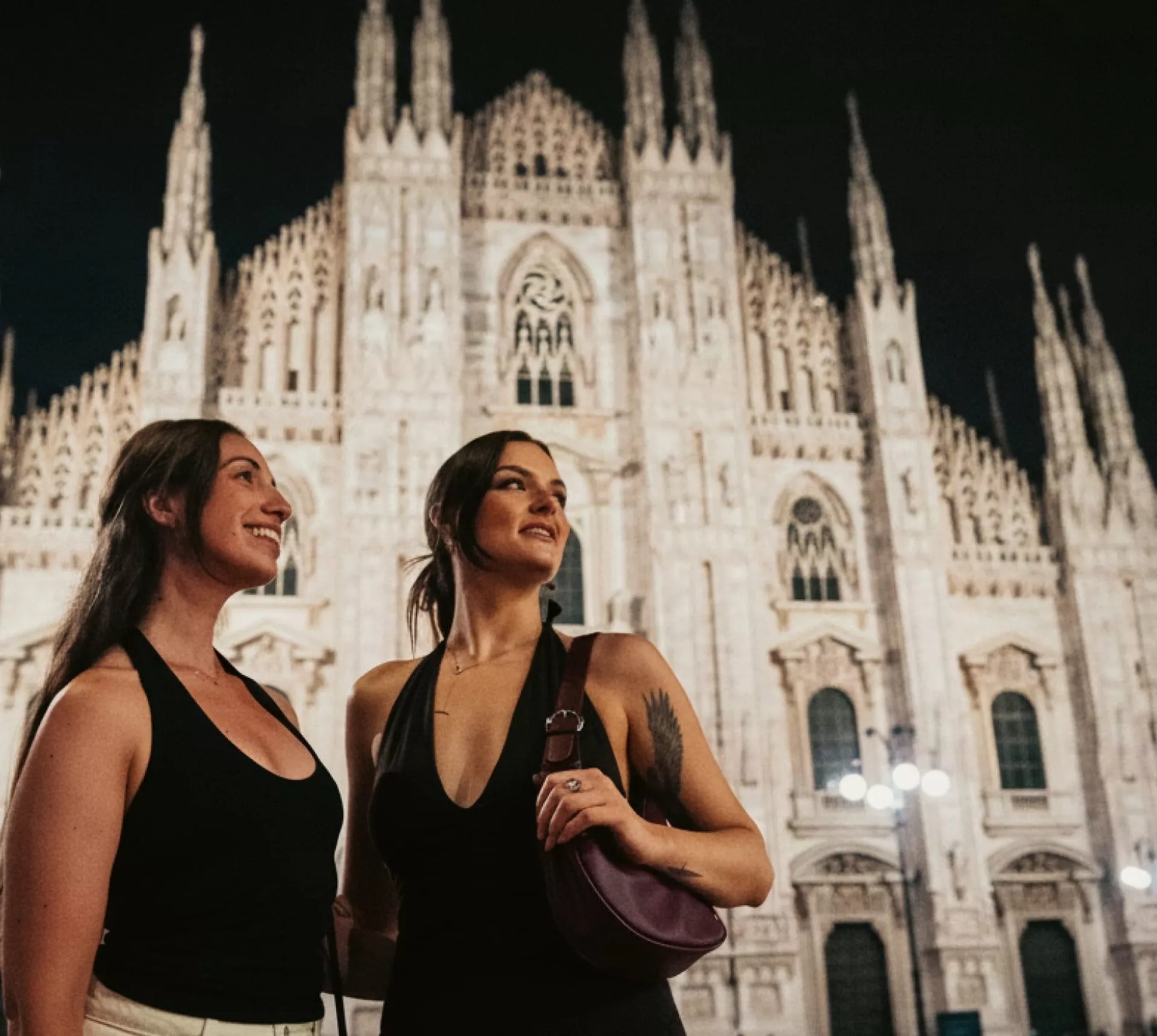 Two girls admiring Milan Cathedral (Duomo di Milano) at night - Contiki Paris to Rome by Train Tour