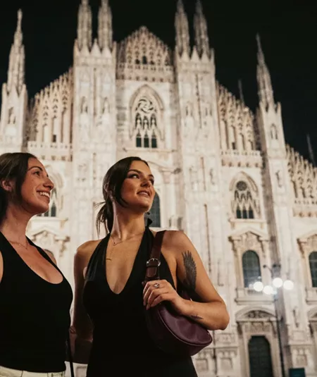 Two girls admiring Milan Cathedral (Duomo di Milano) at night - Contiki Paris to Rome by Train Tour