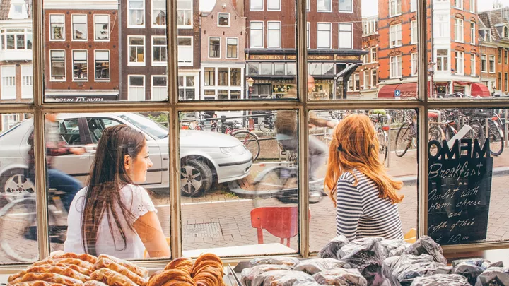 Travellers at a Cafe overlooking a Dutch Canal in Amsterdam, netherlands