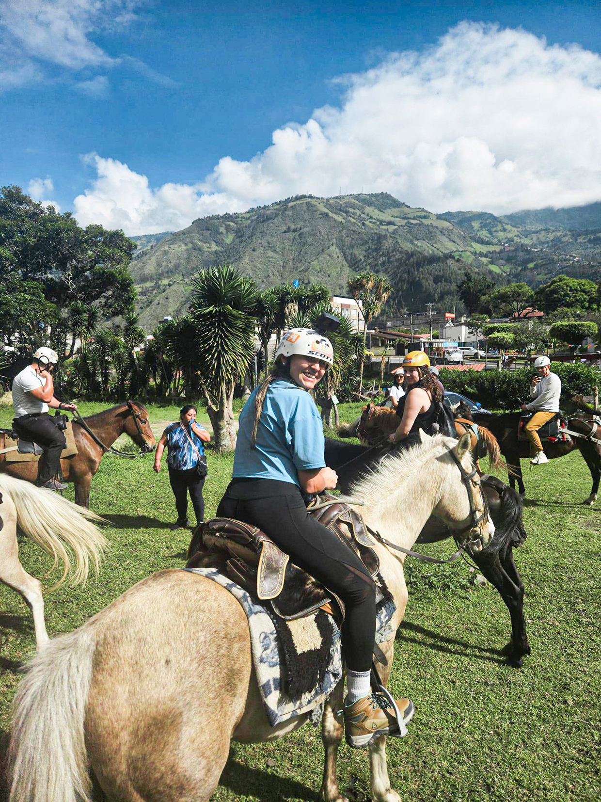 Travellers riding horses with mountains in the background in Baños, Ecuador