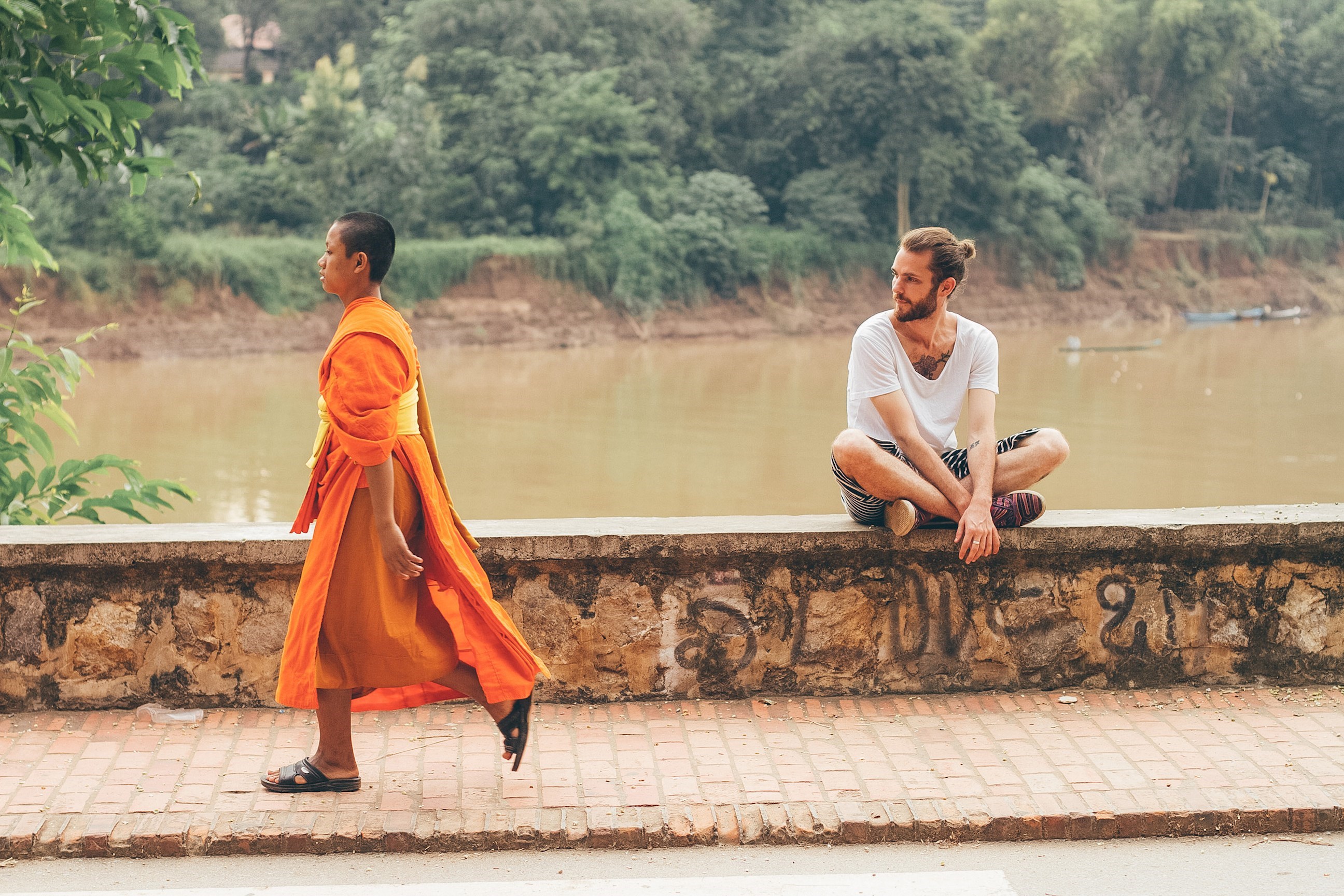 A Buddhist walking along the Nam Khan River in Luang Prabang, Laos