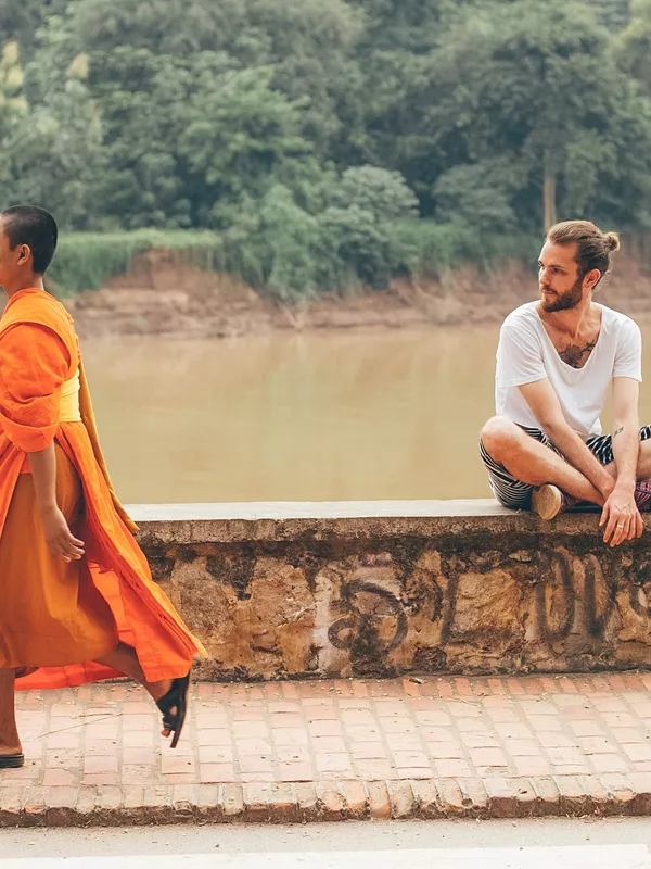 A Buddhist walking along the Nam Khan River in Luang Prabang, Laos