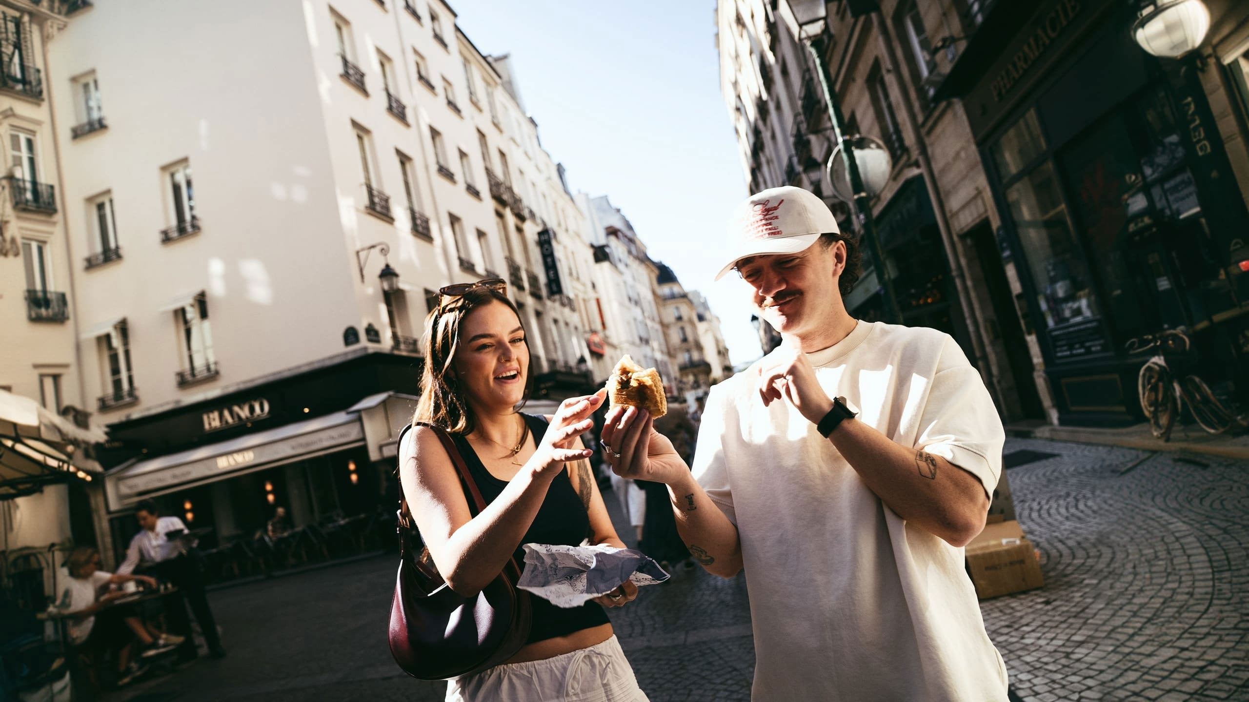 Travellers enjoying a French pastry while exploring a charming street on the Contiki France in a Week Tour
