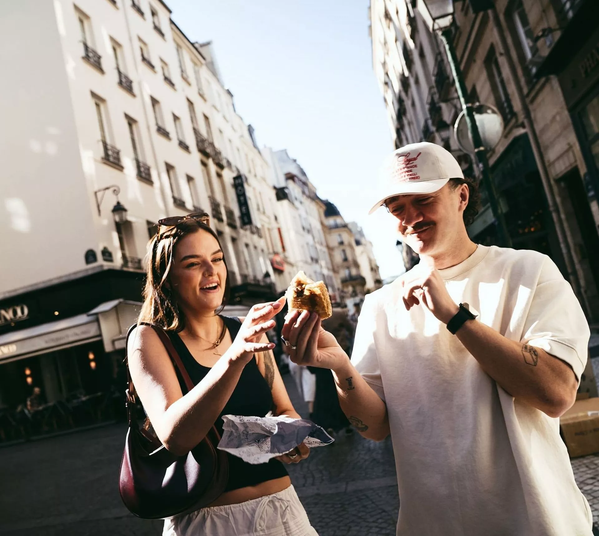 Travellers enjoying a French pastry while exploring a charming street on the Contiki France in a Week Tour