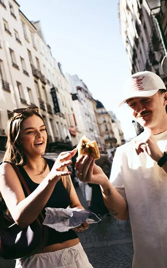 Travellers enjoying a French pastry while exploring a charming street on the Contiki France in a Week Tour