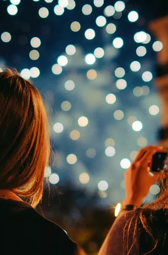 Two young women photographing New Year's Eve fireworks display in Paris France at night - Contiki Paris New Year's Eve Tour