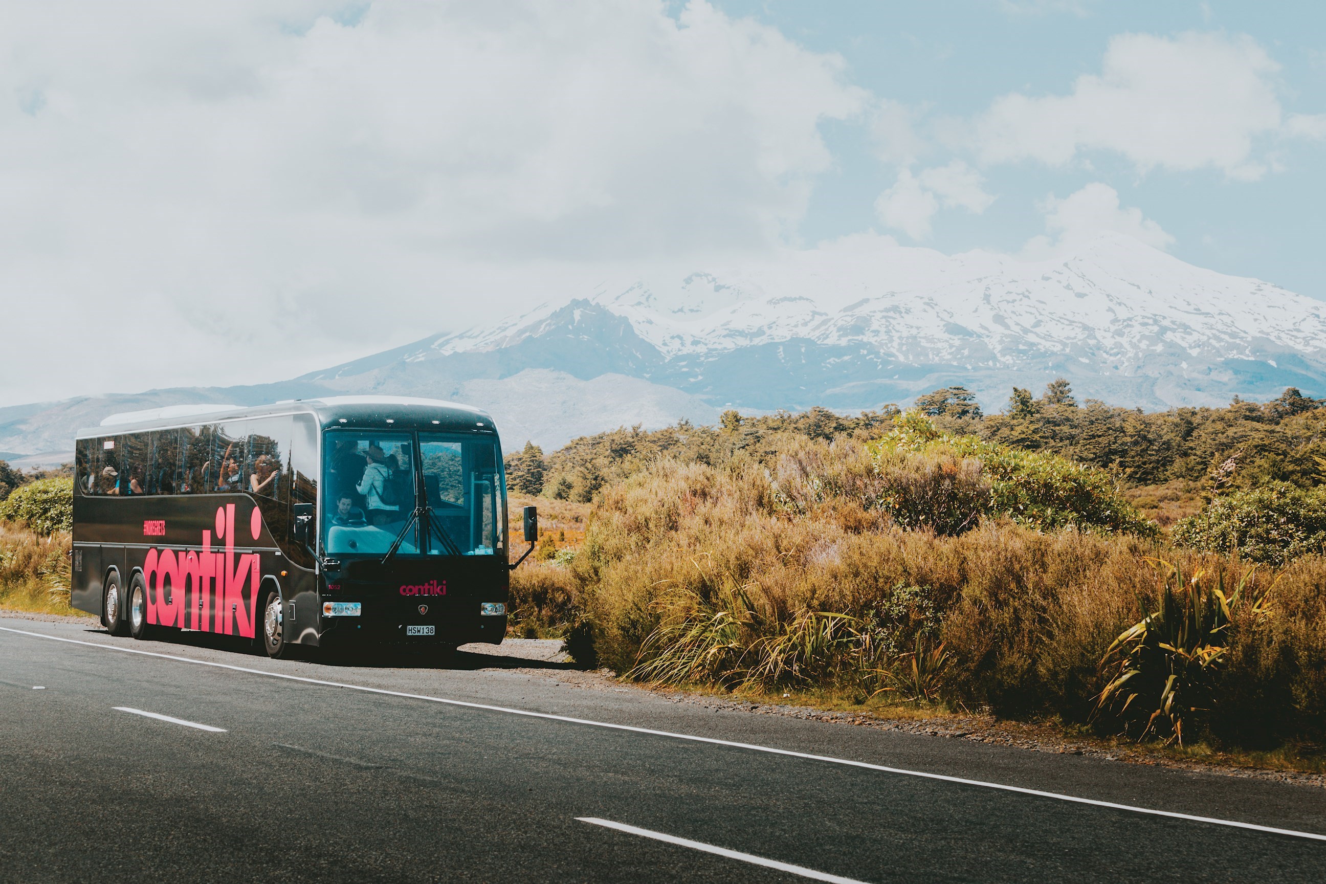 A Contiki Coach in front of the a view of Mount Ruapehu, New Zealand