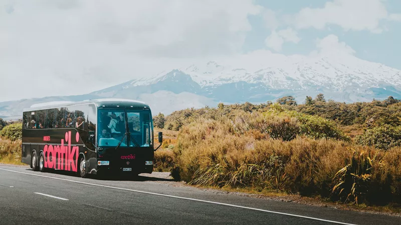 A Contiki Coach in front of the a view of Mount Ruapehu, New Zealand