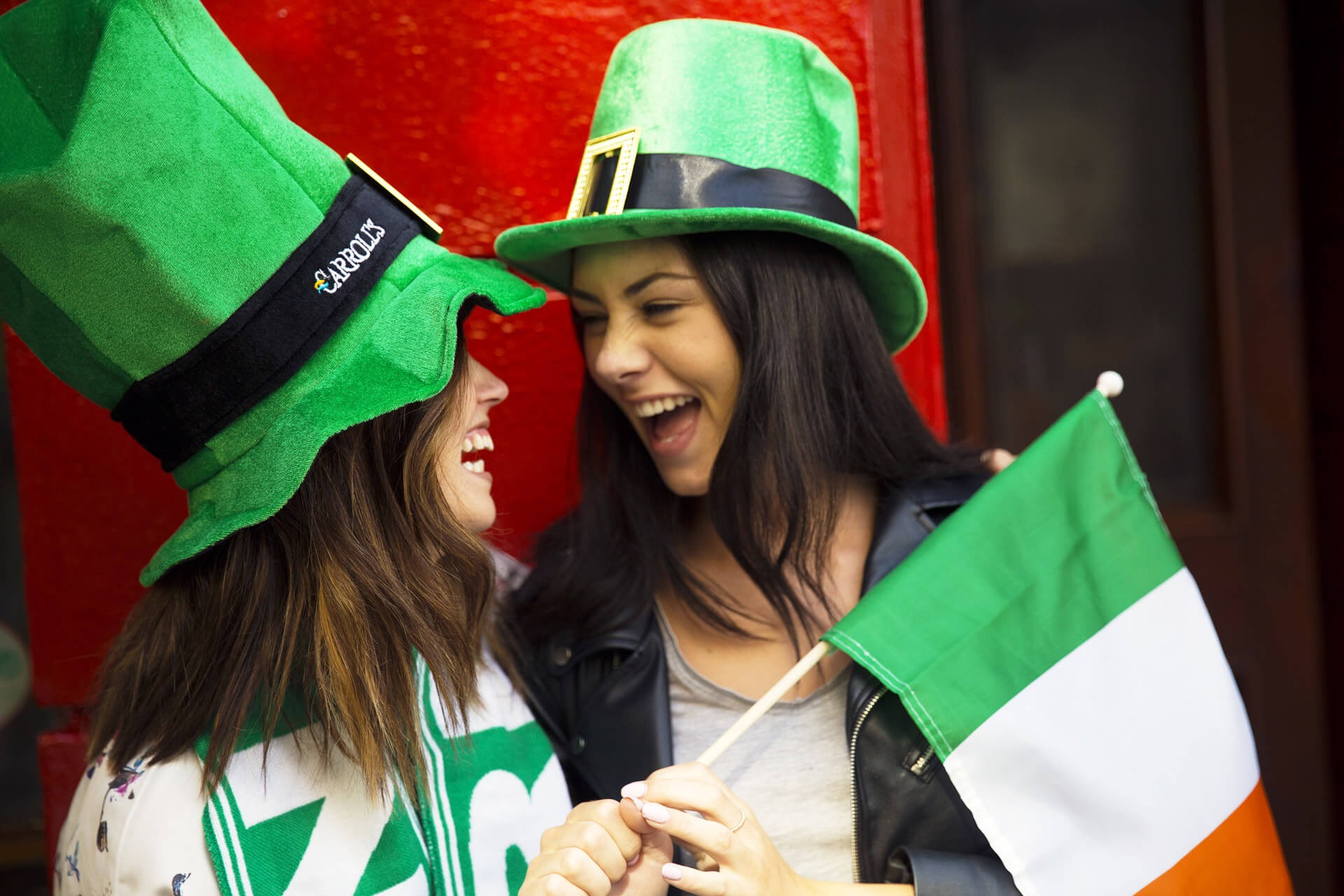 Two women chatting in leprechaun hats holding Irish flag in Dublin, Ireland