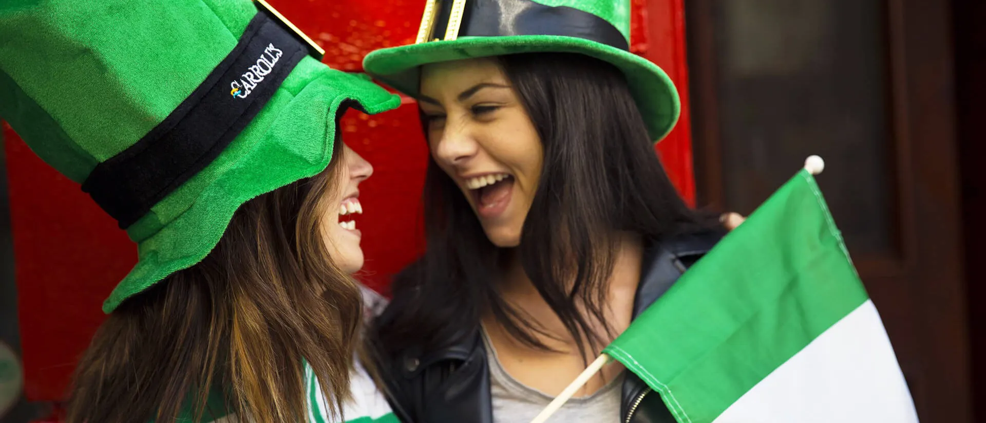 Two women chatting in leprechaun hats holding Irish flag in Dublin, Ireland