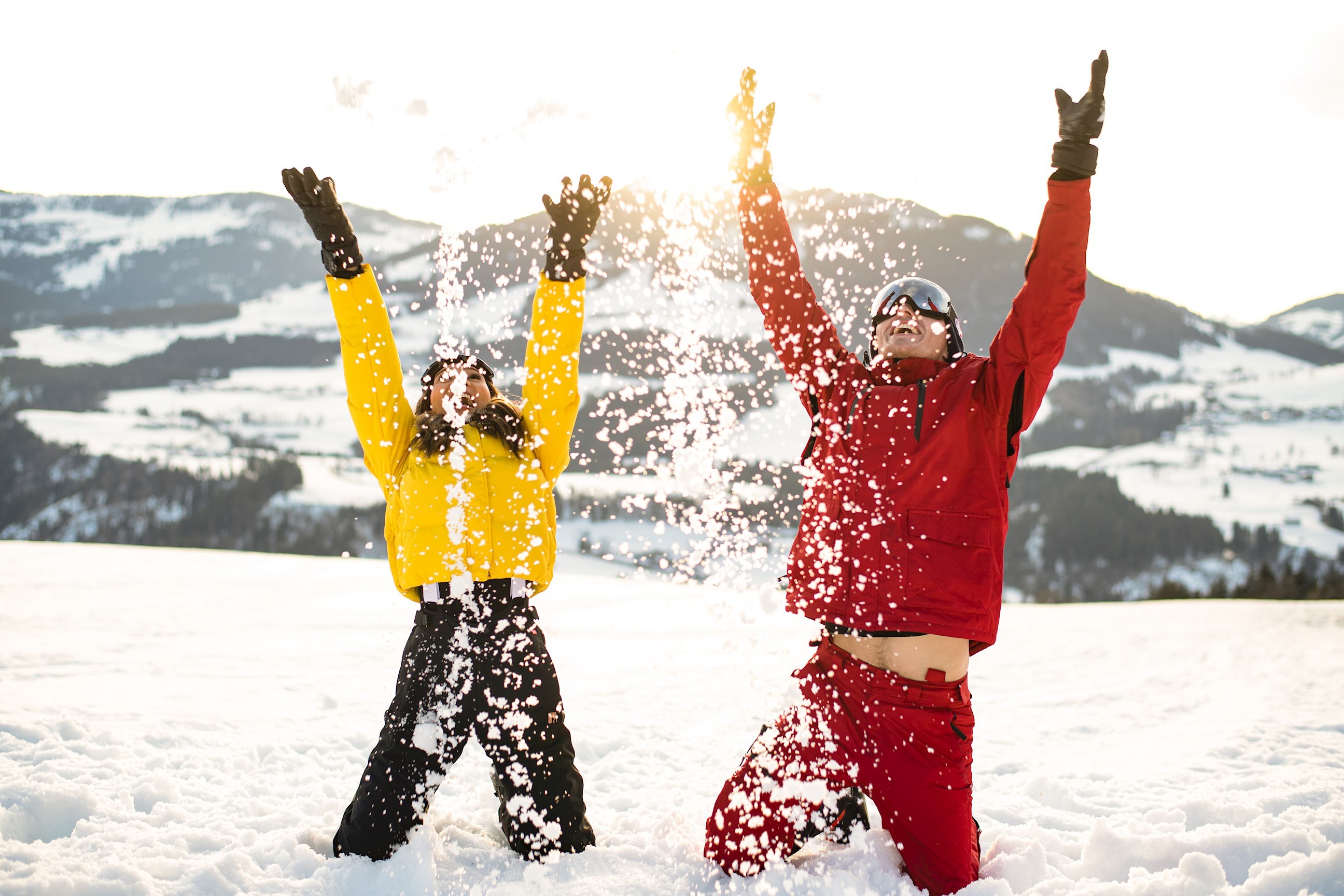 Travellers playing in the snow in front of the Alps in Hopfgarten, Austria